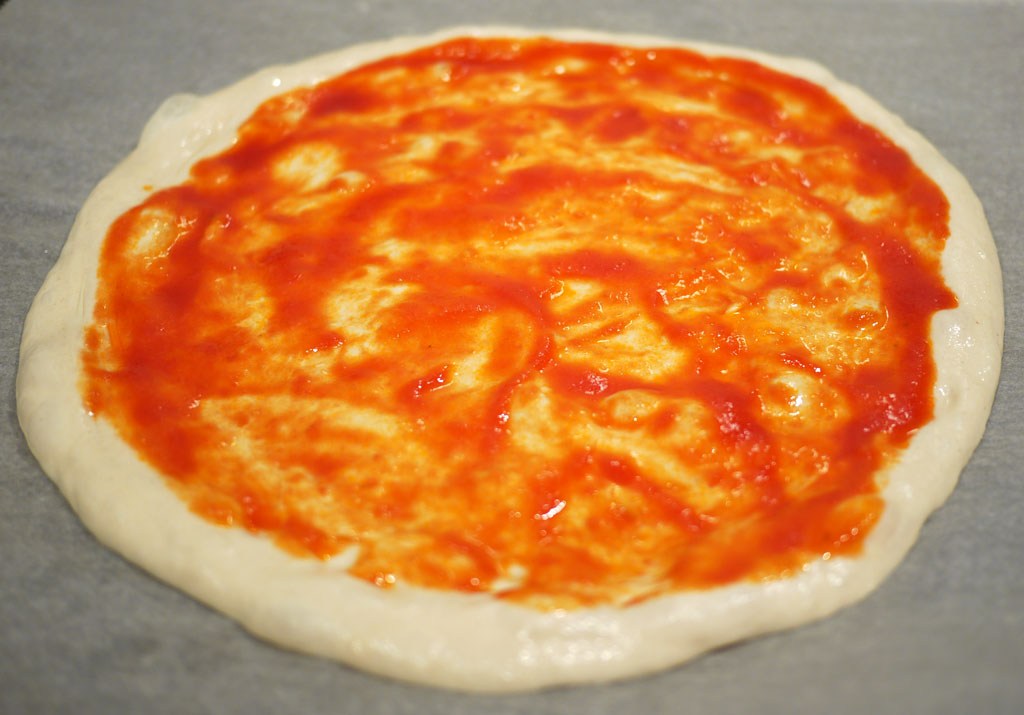 Tomato sauce on unbaked pizza dough